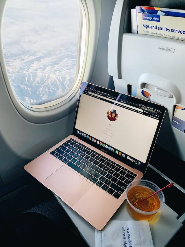 A photo shooted in an airplane, showing a laptop and the window.